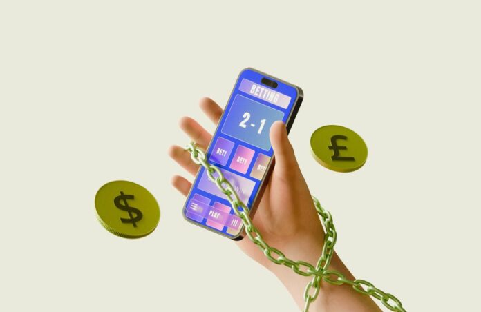Chained hand holding smartphone calculator with dollar and pound coins.