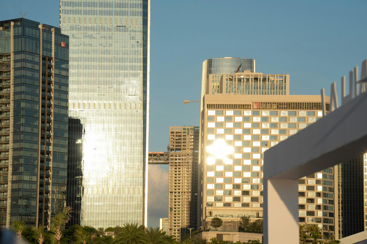 Modern skyscrapers reflecting sunlight against a clear sky.